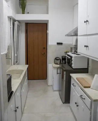 a kitchen with white cabinets and a brown door at Athens view suite in Athens