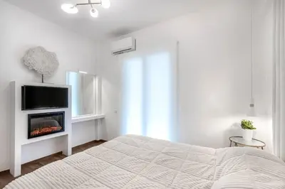 a white bedroom with a bed and a tv at Stylish acropolis view apartment in Athens