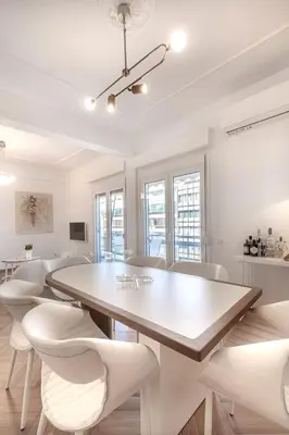 a white dining room with a table and chairs at Stylish acropolis view apartment in Athens