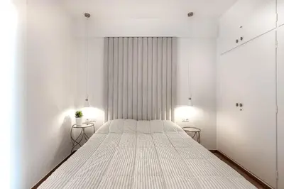 a white bedroom with a large bed with two tables at Stylish acropolis view apartment in Athens