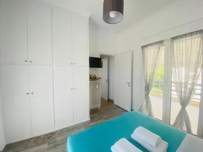 a white room with a blue bed and a window at Acropolis Penthouse - 100Mbps Internet Connection in Athens
