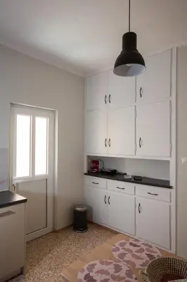 a kitchen with white cabinets and a window at Antigonis Athenian Home in Athens