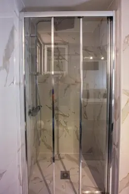 a glass shower in a room with a wall at Antigonis Athenian Home in Athens