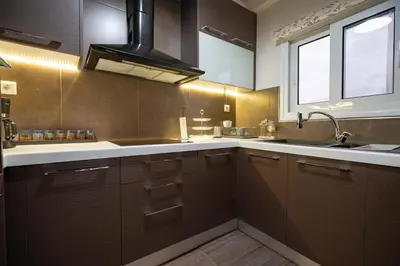 a kitchen with brown cabinets and a sink and a window at Gkyzi Warm Classic Home by ΜΡS in Athens