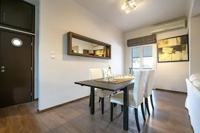 a dining room with a black table and white chairs at Gkyzi Warm Classic Home by ΜΡS in Athens