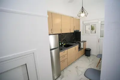 a kitchen with wooden cabinets and a stainless steel refrigerator at The Little Yard Downstairs Apt - Goudi by ΜΡS in Athens