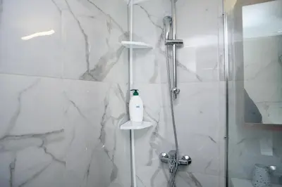 a bathroom with a shower with a glass door at The Little Yard Downstairs Apt - Goudi by ΜΡS in Athens