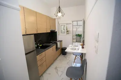 a kitchen with a table and a sink and a refrigerator at The Little Yard Downstairs Apt - Goudi by ΜΡS in Athens