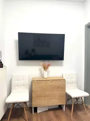 a living room with two white chairs and a tv at Acropolis Traditional Stoney Retreat in Athens