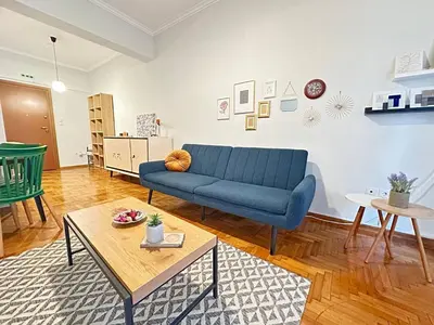 a living room with a blue couch and a table at Cozy Athenian Nest Getaway in Athens