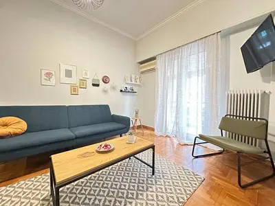 a living room with a blue couch and a table at Cozy Athenian Nest Getaway in Athens