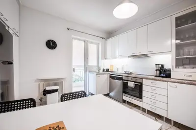 a kitchen with white cabinets and a table and chairs at Elysian Smyrni - Marble Elegance Retreat in Athens