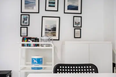 a white room with a chair and pictures on the wall at Elysian Smyrni - Marble Elegance Retreat in Athens