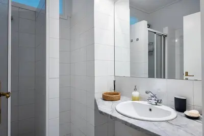 a white bathroom with a sink and a mirror at Elysian Smyrni - Marble Elegance Retreat in Athens