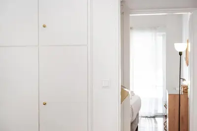 a living room with white cabinets and a bed at Elysian Smyrni - Marble Elegance Retreat in Athens