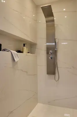 a bathroom with a shower with white marble walls at Villa Riviera in Vari