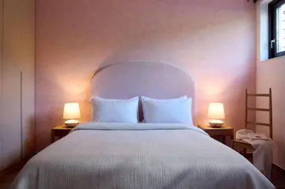 a bedroom with a large white bed with two lamps at Villa Riviera in Vari