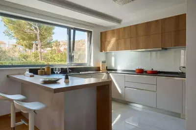 a kitchen with white cabinets and a large window at Villa Riviera in Vari