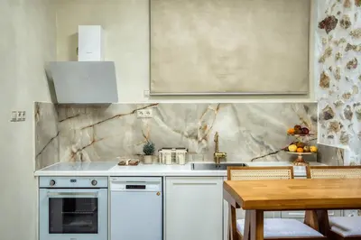 a kitchen with white cabinets and a sink and a table at The Marble Retreat in Athens
