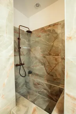 a bathroom with a shower with a stone wall at The Marble Retreat in Athens