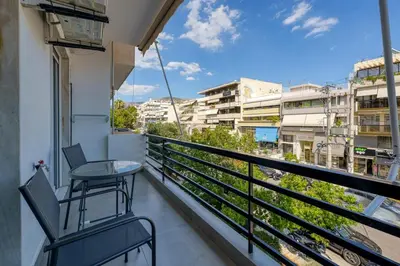 a balcony with a table and chairs and buildings at Chic and Cozy Apartment in the Heart of Glyfada in Athens