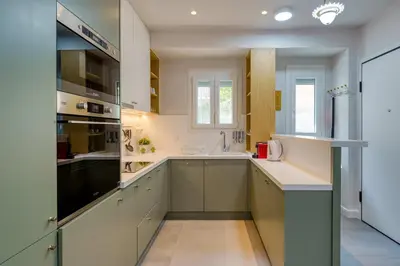 a large kitchen with white cabinets and a sink at Chic and Cozy Apartment in the Heart of Glyfada in Athens