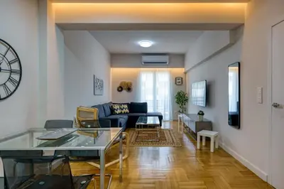 a living room with a couch and a clock on the wall at Chic and Cozy Apartment in the Heart of Glyfada in Athens