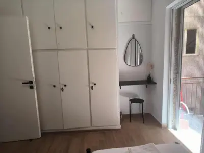 a bedroom with white cabinets and a table and a chair at Casa Dili Stylish 2BR Apartment in Athens