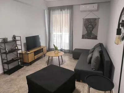 a living room with a black couch and a table at Casa Dili Stylish 2BR Apartment in Athens