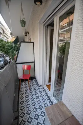 a red chair sitting on a balcony next to a window at Pop Art Escape - Zografou by ΜΡS in Athens