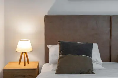 a bed with a pillow and a lamp on a table at Acropolis Oasis - 2BR, Koukaki in Athens