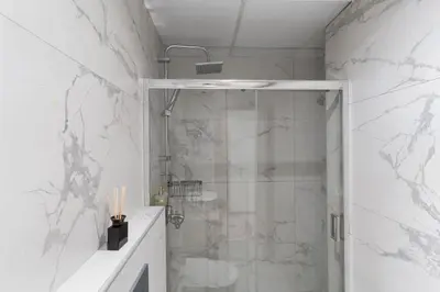 a bathroom with a shower with a glass door at Acropolis Oasis - 2BR, Koukaki in Athens