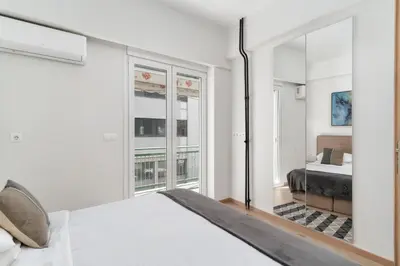 a white bedroom with a bed and a window at Acropolis Oasis - 2BR, Koukaki in Athens