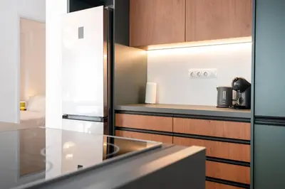 a kitchen with a stainless steel refrigerator and wooden cabinets at Navarino Athenian Nest in Athens