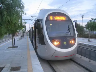 a white train is pulling up to a station at Beachside Apartment - Available per month in Athens