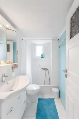 a white bathroom with a sink and a toilet at Beachside Apartment - Available per month in Athens