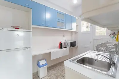 a white kitchen with blue cabinets and a sink at Beachside Apartment - Available per month in Athens