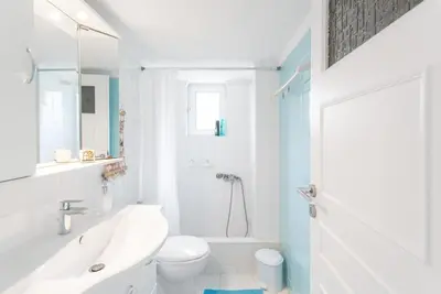 a white bathroom with a sink and a toilet at Beachside Apartment - Available per month in Athens