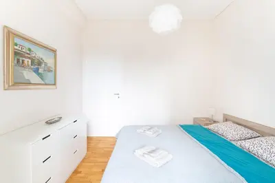 a white bedroom with a bed and a dresser at Beachside Apartment - Available per month in Athens