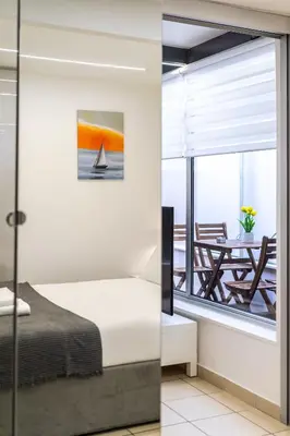 a bedroom with a window with a bed and a table at Urban Patio Apartment in Athens