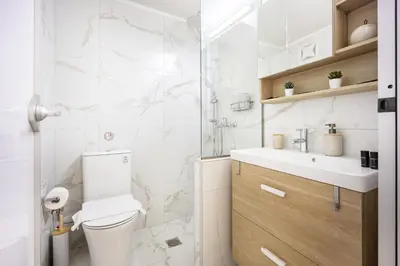 a white bathroom with a toilet and a sink at Urban Patio Apartment in Athens