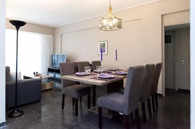 a dining room with a table with chairs and a television at Modern Comfort 2 bdrm Apartment in Voula in Athens