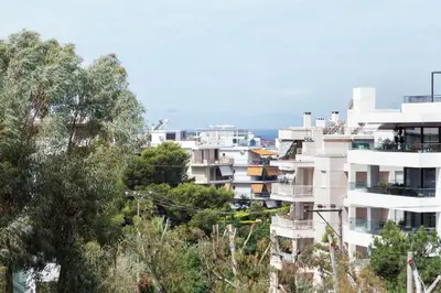 a tall white building with trees in front of it at Modern Comfort 2 bdrm Apartment in Voula in Athens