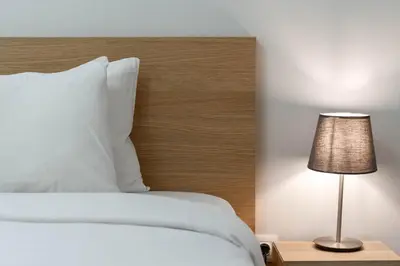 a bed with a wooden headboard next to a lamp at Urban Nest - Studio, Neos Kosmos in Athens