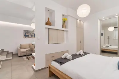 a white bedroom with a bed and a living room at Urban Nest - Studio, Neos Kosmos in Athens