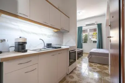 a kitchen with white cabinets and a sink and a bed at Petrαlonα 1-Bdr cοmfort, neαr Metro by Traser in Athens