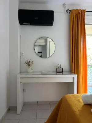a dressing table with a mirror and a television on a wall at MediTerra Stay Voula Beach in Athens