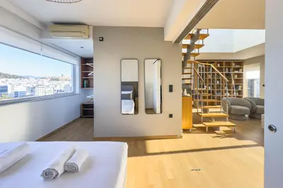 a room with a large window and a living room with a staircase at Acropolis Sky Retreat Jacuzzi & 3BR Maisonette in Athens