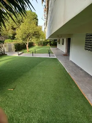 a yard with green grass next to a building at Sea and City Voula Suite by First Class Properties in Athens