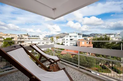 a rocking chair on a balcony with a view of a city at Sea and City Voula Suite by First Class Properties in Athens